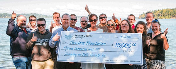 Most of The Freedom Foundation's staff poses jubilantly with a giant replica of a check from Island County for $15