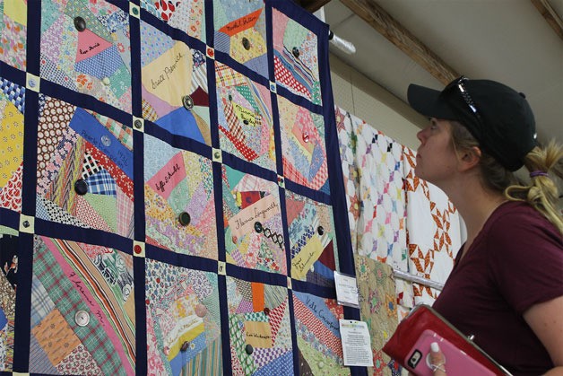 Clinton resident Kimberly Boenish examines the “Friendship Quilt” Thursday afternoon in the Malone Building at the Whidbey Island Fair. The fabrics used in the quilt were crafted by a group of Maxwelton women in 1936.