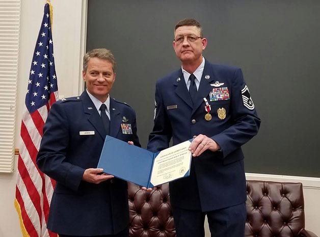 U.S. Air Force Colonel Kendall B James (left) presents Senior Master Sgt. Kelly Henderson (right) with a certificate of appreciation from President Barack Obama during Henderson’s retirement ceremony earlier this month.