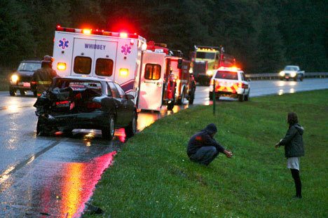 The occupants of a Chevy pickup that hit another vehicle on Highway 525 near Crawford Road wait by the roadside after the Monday afternoon crash.