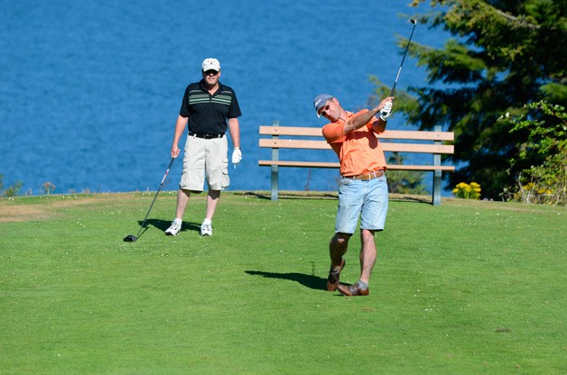Craig Moore plays golf at Holmes Harbor while Paul Kiernan looks on. A dispute over parking may soon be fought in court.