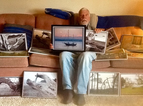 Langley photographer Ed Severinghaus holds photos that he's taken over 20 years. An exhibit and sale begins Friday at the Deer Lagoon Grange.