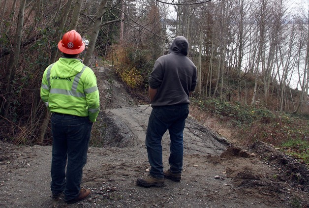 Asplundh workers survey the damage to a section of Driftwood Way that dropped eight feet over a few days.