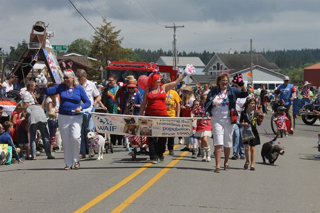 Whidbey Animals Improvement Foundation supporters walk down Maxwelton Road during the 101st Maxwelton independence Day Parade Monday. More than 2