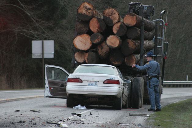 A State Trooper with the State Patrol helps investigate a collision between a Ford Taurus and a logging truck south of Freeland Wednesday morning.