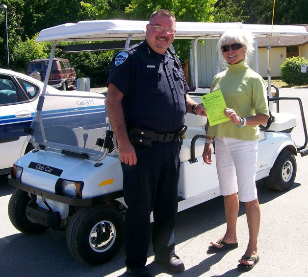 Chief Randy Heston of the City of Langley Police Department and Janet Ploof show off the first Langley golf cart permit for a street legal six-person cart to shuttle fairgoers between the marina