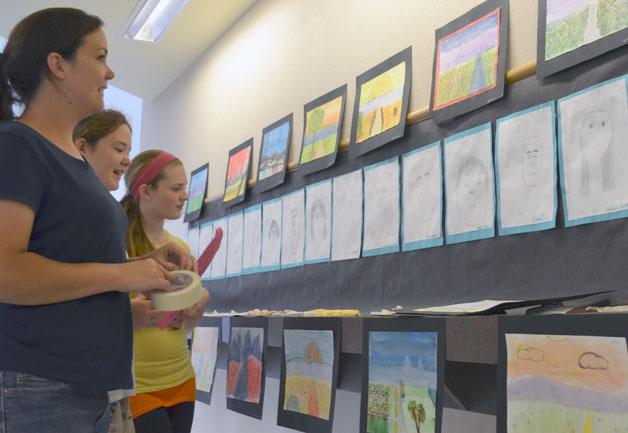 Chloe Loehr and Mya Pratt set up artwork from their fifth-grade class with Rose Tosh