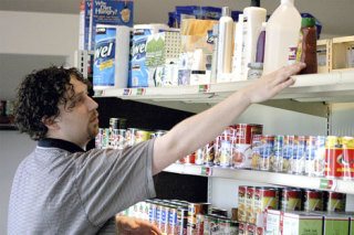 Newly-appointed food bank coordinator Damien Cortez stocks the shelves at Good Cheer Food Bank in Bayview Friday morning.