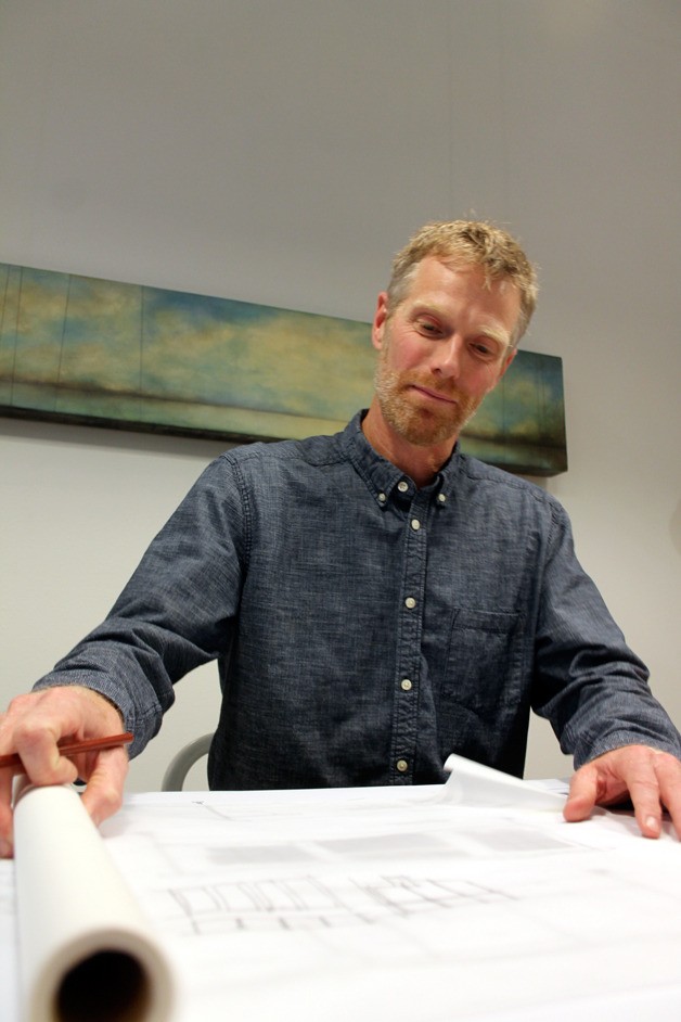 David Price rolls some sketch paper over a design print for a San Juan Islands home design inside his new store in Langley which is part gallery