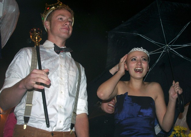 South Whidbey High School senior Sam Turpin presides over the crowd with his homecoming crown and scepter Friday night. Homecoming queen Lennox Bishop laughs while trying to stay dry during the halftime coronation.