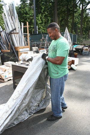 Volunteer Richard Stroter folds up a tarp cover at the BaRC Re-tail store in Coupeville on Monday.