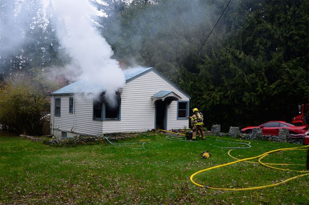 Two South Whidbey Fire/EMS firefighters prepare to enter a burning home on Langley Road on Monday following a storm. The fire started when the power came back on