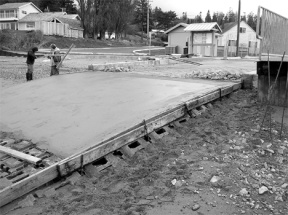 Workers put the finishing touches on a new concrete pad at the Bush Point boat launch ramp late last month. The ramp will open April 8 after floats are installed.