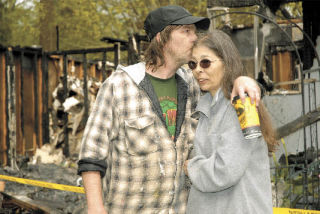 Chris and Lois Smith comfort each other in front of their ruined Langley home.