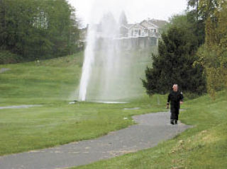 Fire District 3 Deputy Chief Mike Cotton surveys running water leading away from a water main leak at Holmes Harbor Golf and Beach Club early Sunday morning.