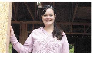 Rose Tosh stands outside her new home. The Habitat for Humanity volunteers are building her new house in a week.