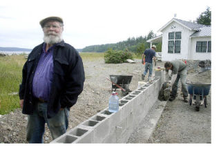 Glen Russell stands next to a wall being built by the Montgomery family near the beach access by Greenbank Farm. Russell is worried the Montgomerys are encroaching on the county road that leads to the beach. County officials asked the Montgomerys to stop building the wall