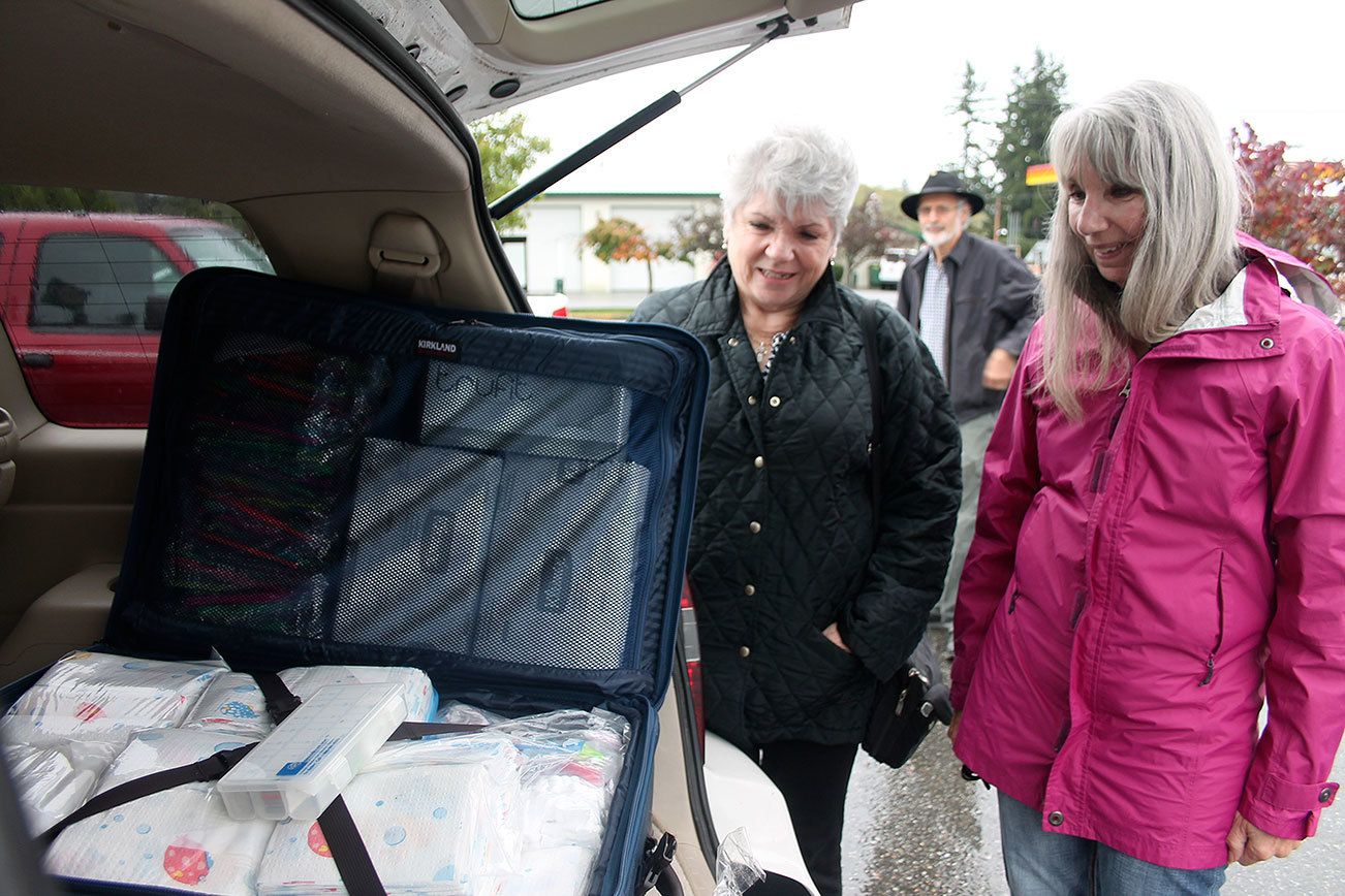 Kyle Jensen / The Record South Whidbey volunteers Marti Bauer (left) and Linda Jacobson (right) take a look at one of the 16 bags the volunteers will take on their aid trip to Haiti.