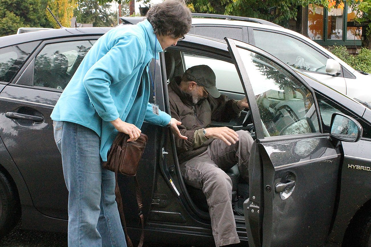 Evan Thompson / The Record South Whidbey at Home volunteer Janice O’Mahony helps member Brad Walker out of her Toyota Prius on Thursday morning.