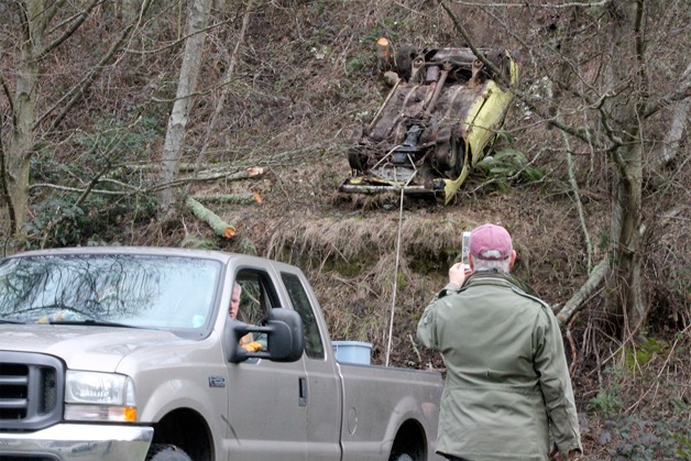 Kevin Lungren drives away from the Clinton hillside with the abandoned Mazda coupe flipped over while Fred Lundahl takes video of the endeavor Feb. 3.