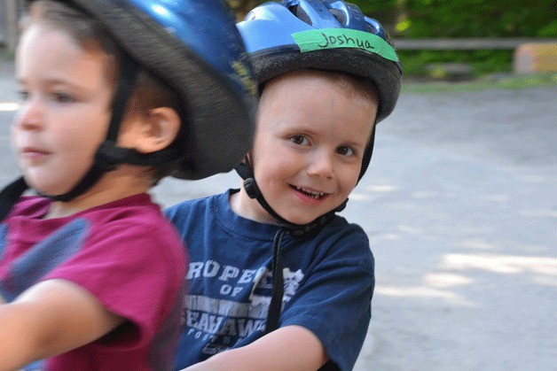 Joshua Furlong enjoys the ride on a two-seat tricycle while classmate Mason Guzman pedals.