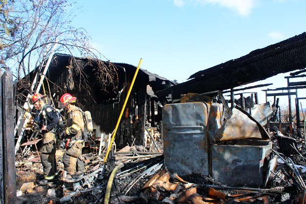 Firefighters inspect the wreckage of a house fire on North Whidbey on Tuesday.