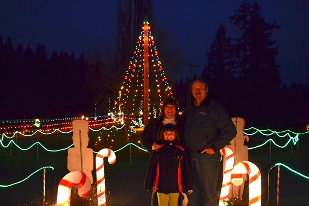 Lois and Jerry Beck stand with 8-year-old Kiki in front of the Christmas lights at their house. This is the 18th year the Beck family has put together the annual Christmas Light Show for guests to drive through. The show is open from 6 to 9 p.m. daily through the end of the year.