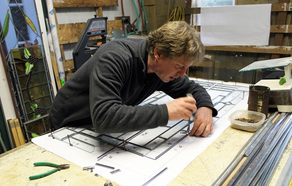 Clinton resident Dennis Meszaros works on a window panel at his studio. Meszaros’ work will be featured on an upcoming episode of Animal Planet’s “Treehouse Masters.”