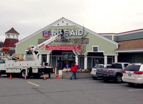 A worker installs the new Rite Aid sign above the door of the late Linds Freeland Pharmacy.