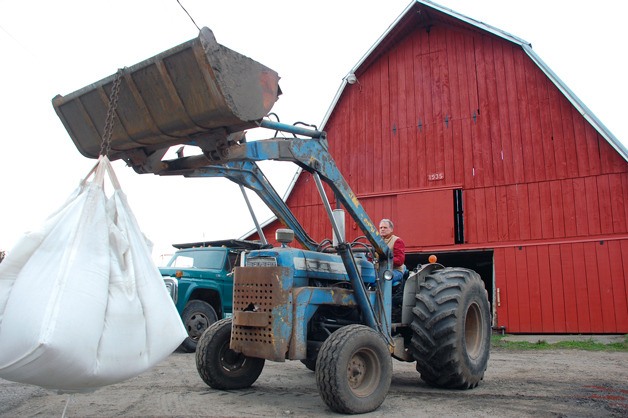 Central Whidbey Farmer Don Sherman sits on his tractor in front of the barn his grandfather