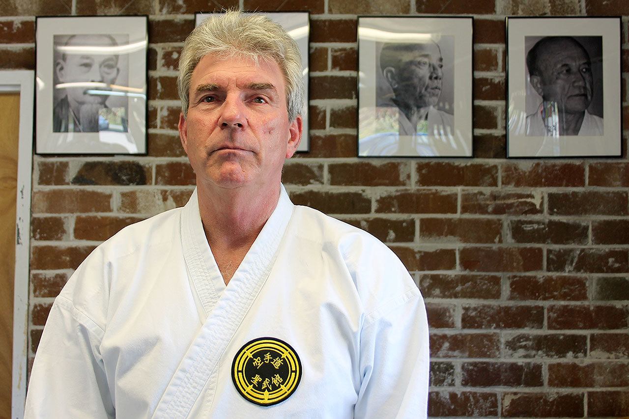 Kyle Jensen / The Record Sensei Warren Berto stands in front of photos of his senseis, who are part of the direct lineage of the Seibukan karate style.