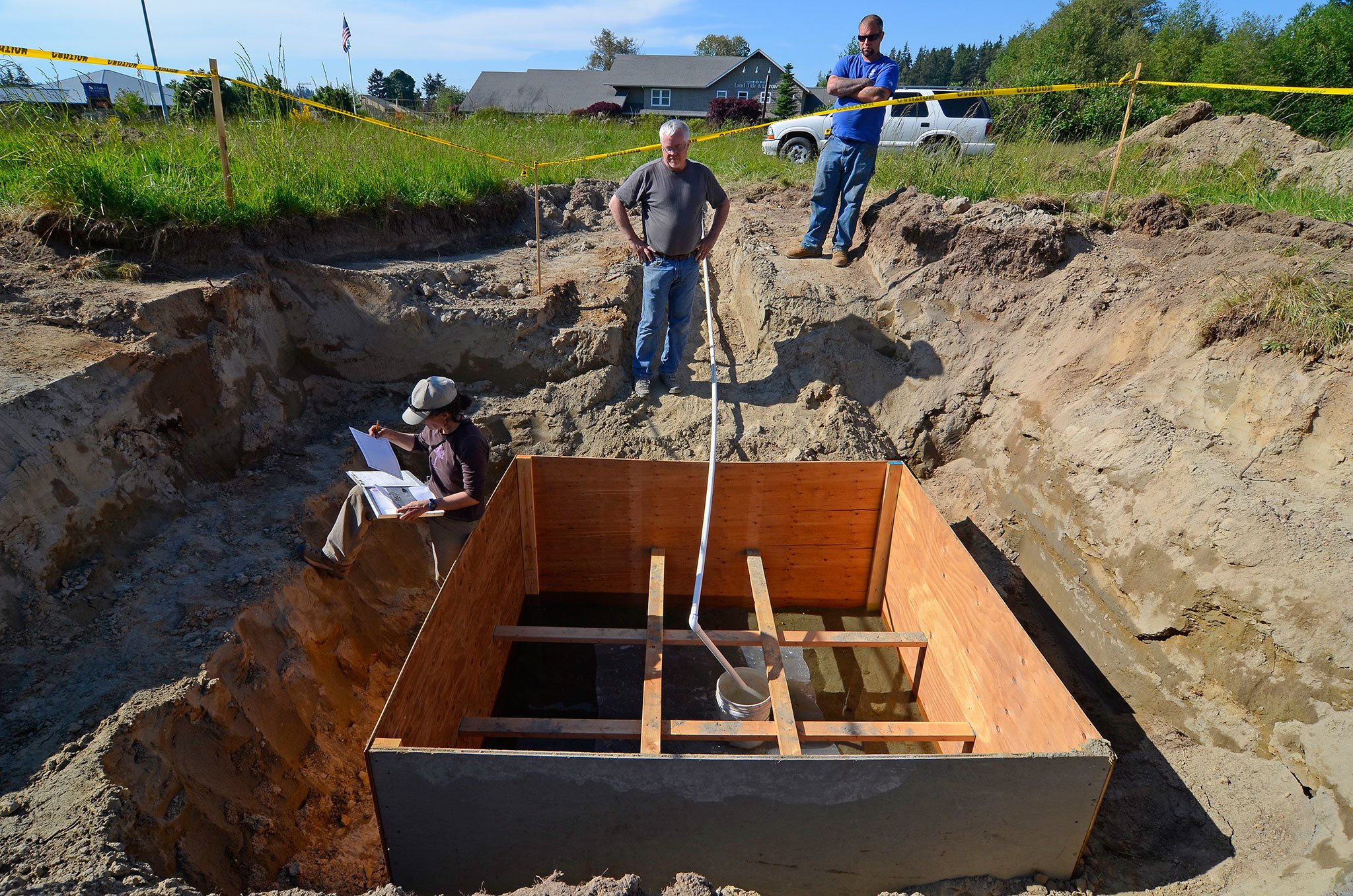 Dawn M. Chapel, a hydrogeologist with Pacific Groundwater Group, marks down drainage rates at one of several test pits in May of 2015 on a 24-acre property off Highway 525. The Freeland Water Sewer District had several tests performed prior to purchasing the land late last year for the phase 1 A sewer project. District commissioners recently learned, however, the technology it planned to utilize to disperse treated effluent back into the ground may be more expensive and less effective than initially believed, putting the property’s viability for infiltration into question.