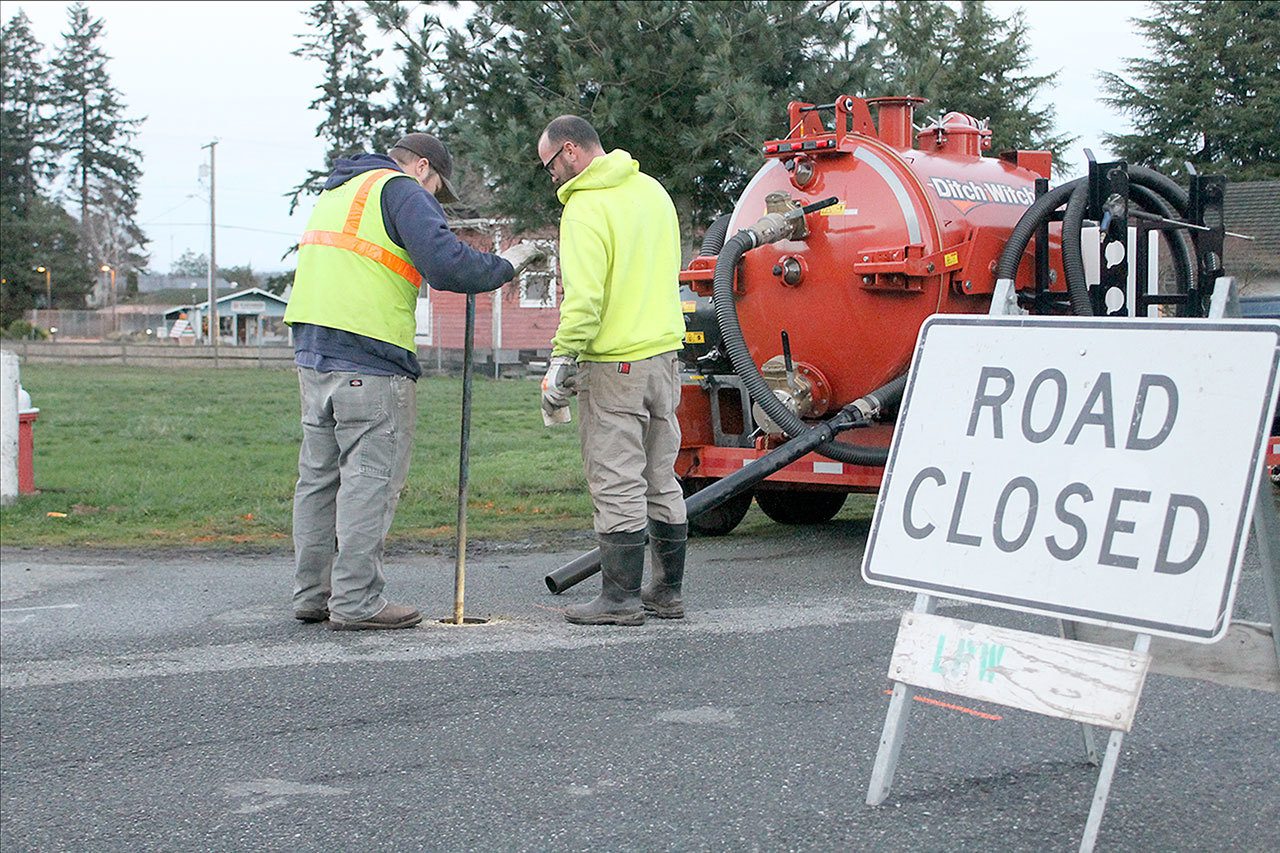 Evan Thompson / The Record                                Two Langley public works employees use a tool to turn water back on for residents around Third Street following the fracture of a water main line. Residents in the area will be without water for a couple hours today as repairs are made to the pipe.