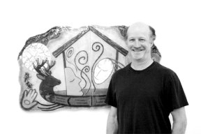 Richard La Londe stands in front of his fused glass pictorial piece "Spirit Dream" in his Freeland studio. At left is the cover of his new book