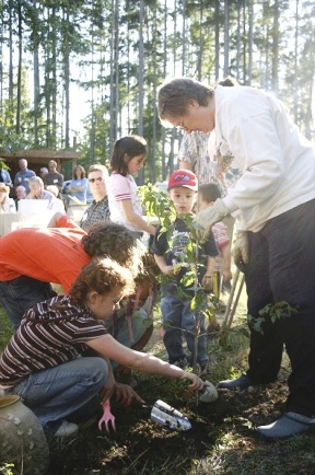 Marjorie Lohrer of the Unitarian Universalist Congregation of Whidbey Island helps children from the church plant a tree during the groundbreaking for a new church Sunday.