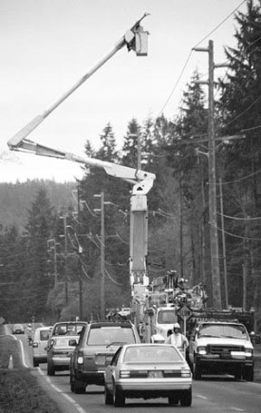 A PSE crew moves poles and wires last week as traffic moves in one lane on Highway 525 north of Freeland. Construction-related delays in the Greenbank area could persist through 2003.