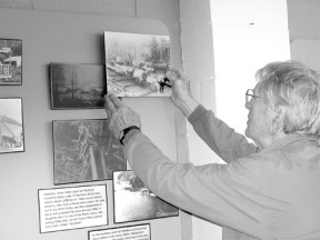 Lee Wexler patiently mounts an historical photo of Clinton on the wall of the Clinton Community hall
