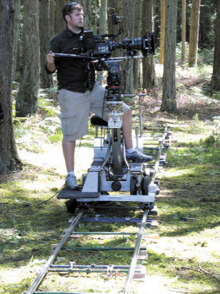Seattle film crew cameraman Mike Prevette sets up his camera on a 30-foot track in the forest next to Bayview Road Wednesday. Lenz Films was filming a woman bicyclist for an ad showing the health benefits of the Everett Clinic.