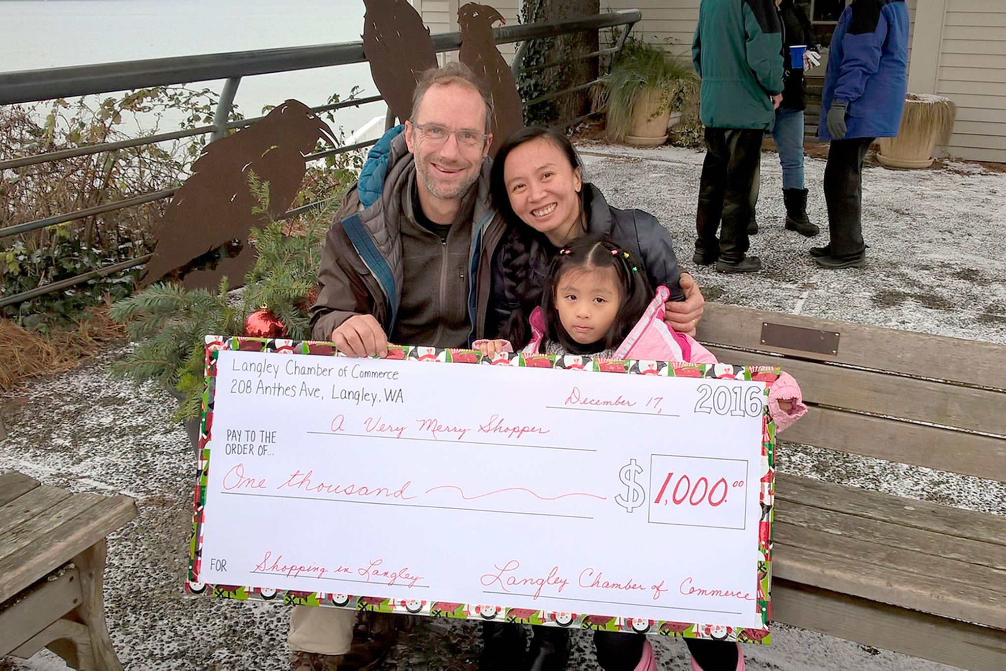 Contributed photo                                Brad Hankins and Ye Chan of Langley hold up a check for $1,000. Chan was the recipient of the “Very Merry $1,000 Giveaway” on Saturday, Dec. 17 at Boy and Dog Park.