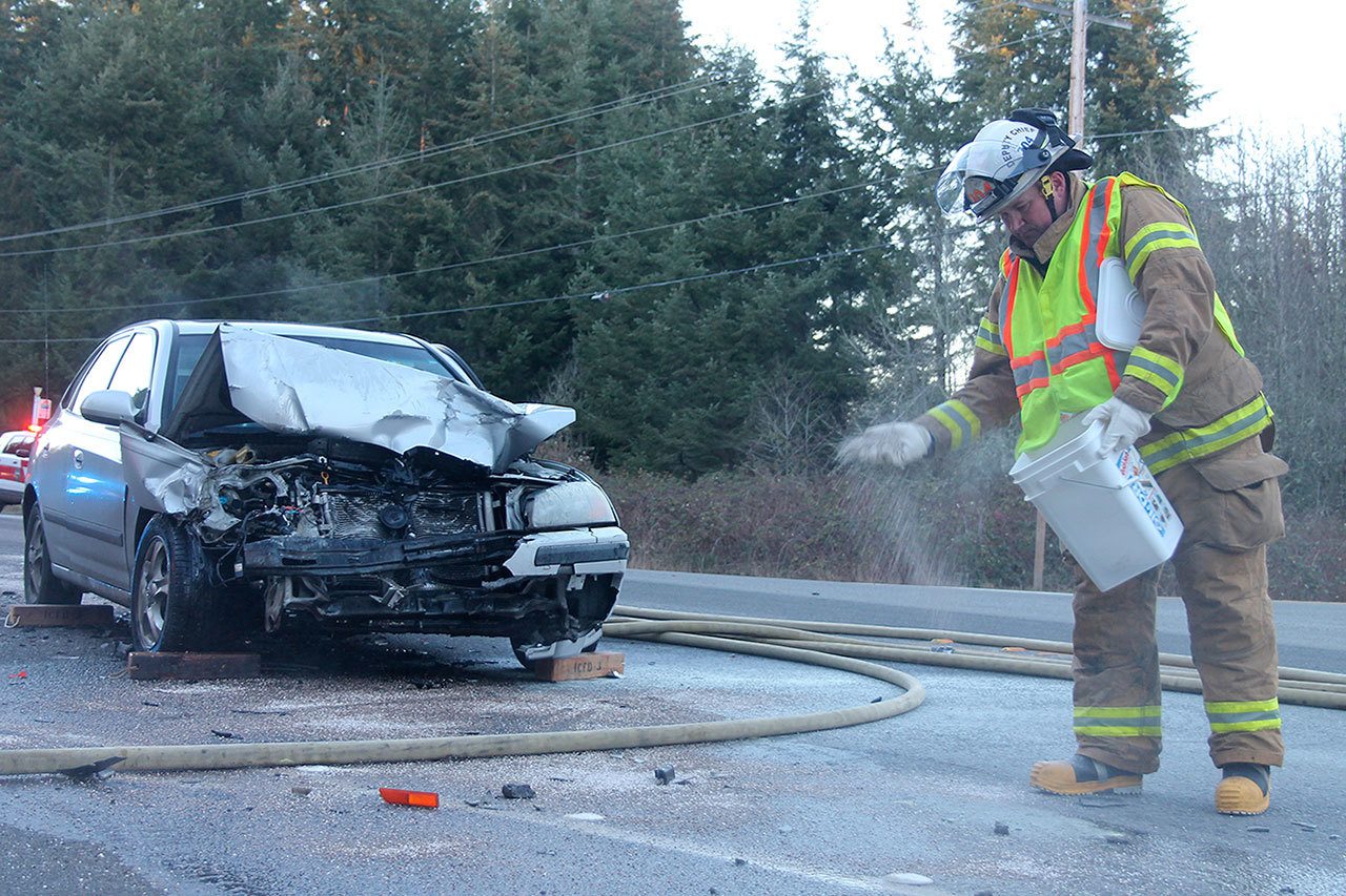 Kyle Jensen / The Record                                Deputy Chief Jon Beck salts southbound Highway 525 after firefighters had to hose down the hood of the Hyundai Elantra, pictured. The water froze shortly after putting out the small flames. It was in the upper &rsquo;20s at the time of the wreck.
