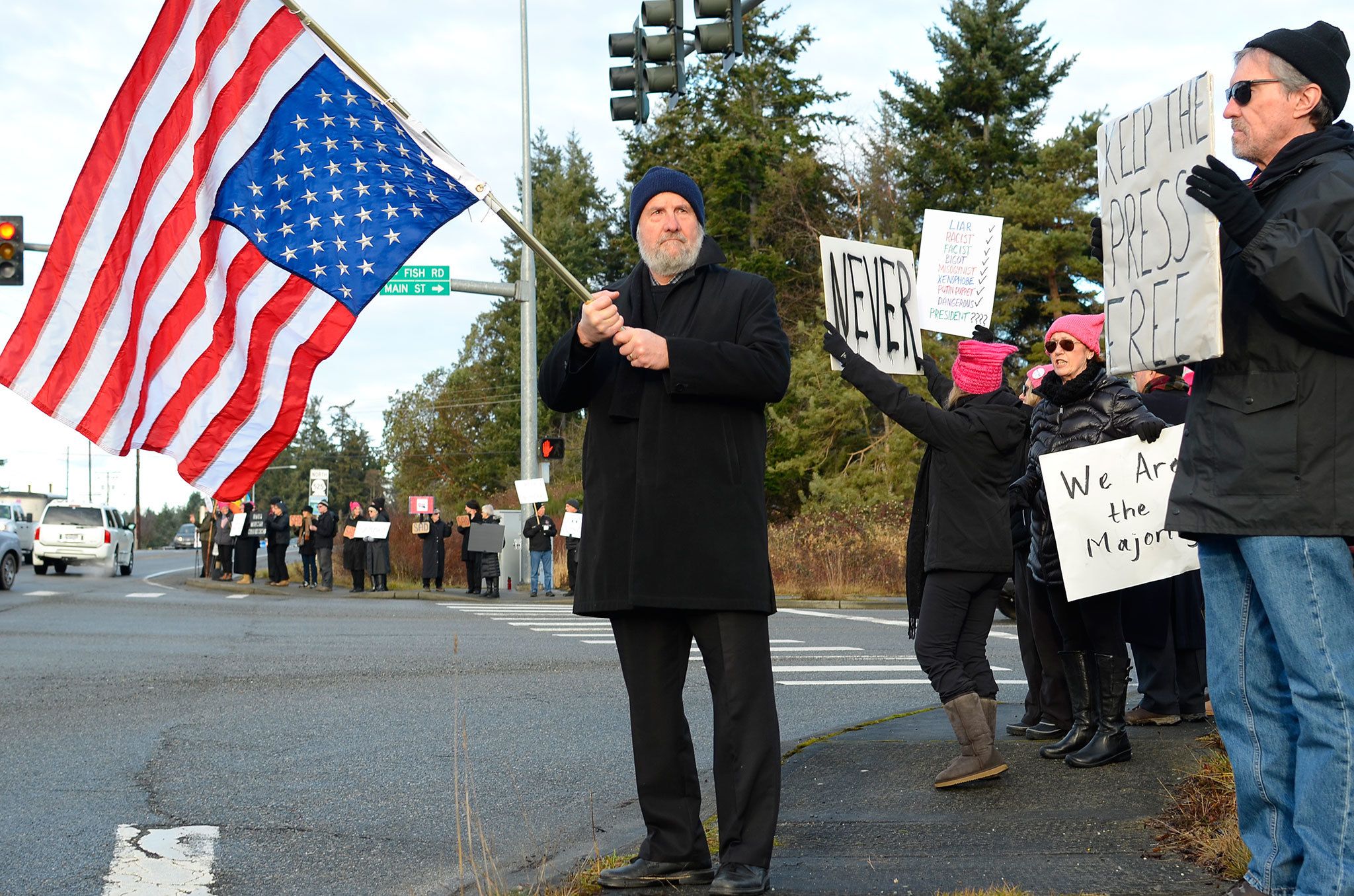 Justin Burnett / The Record —                                Coupeville resident Gary Piazzon waves the American flag during a protest in Freeland on Friday of the inauguration of President Donald Trump.