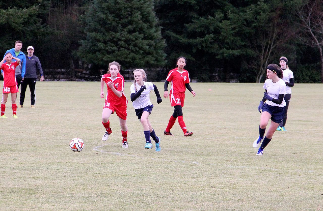 Contributed photo — The South Whidbey Reign U-14 girls, wearing white, beat Issaquah Select FC 3-1 at South Whidbey Sports Complex. Makenna Wicher, left, dribbles the ball on a break away as Kelly Murnane (right) provides an option.