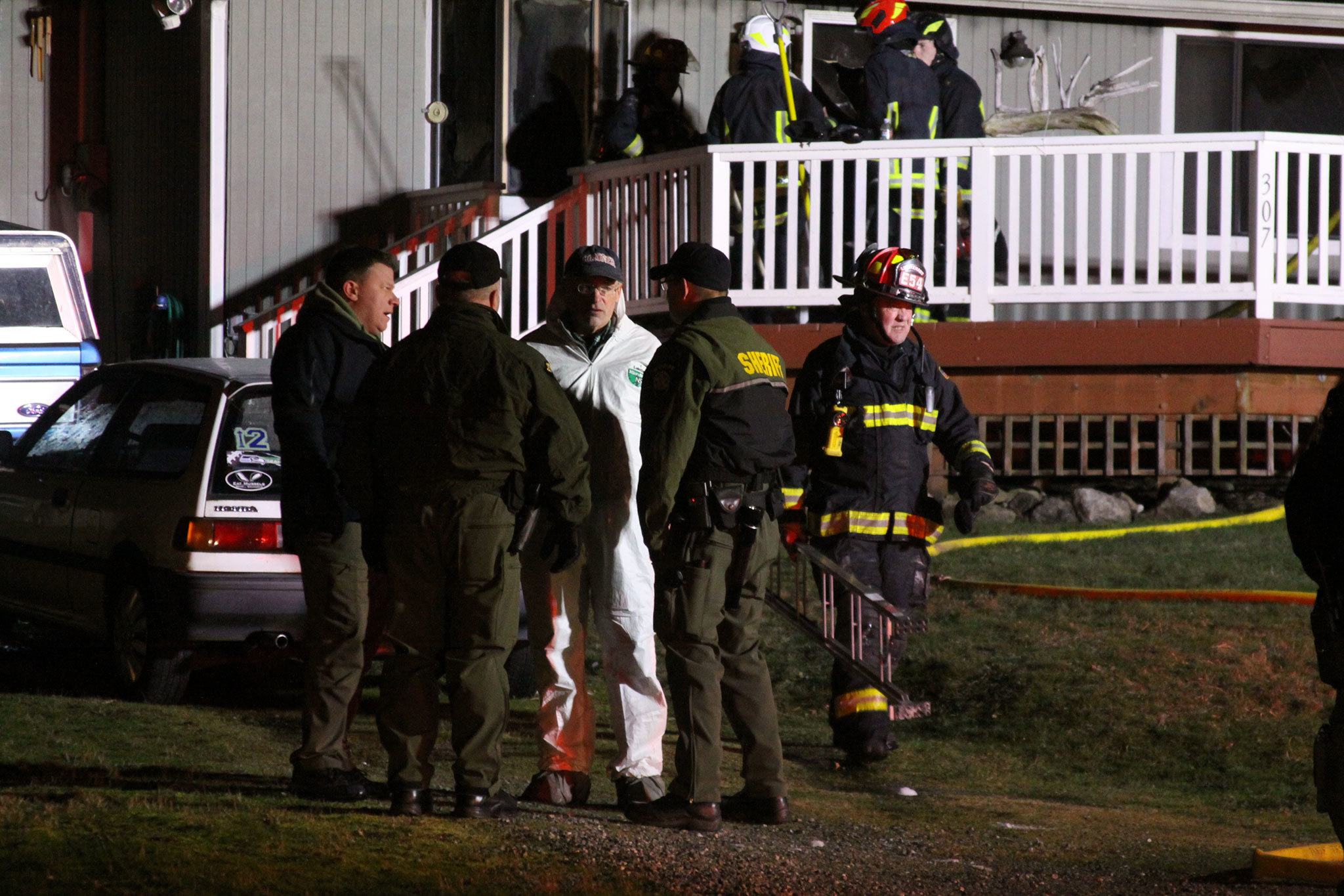 Island County Coroner Robert Bishop, center, meets with members of the Island County&rsquo;s Sheriff&rsquo;s Office after Bishop returned from the house where a Coupeville resident died in a fire Friday night. Photo by Ron Newberry/Whidbey News-Times