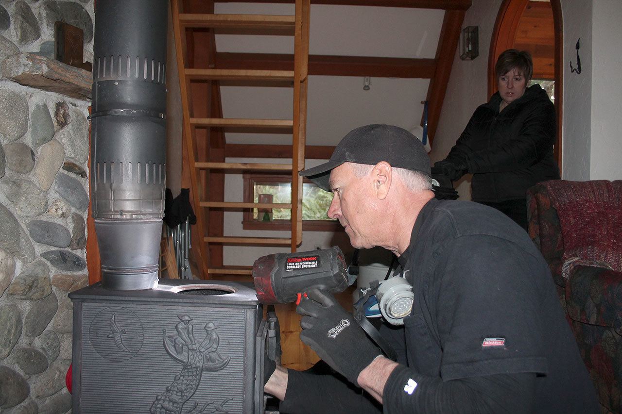 Kyle Jensen / The Record — All Serv Chimney Services owner Rick Hixon and partner Missy Hixon examine a wood stove at Hedgebrook cabin in Langley.