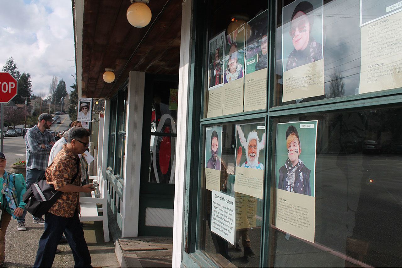 Record file — Pictures of the characters from last year’s Mystery Weekend are posted outside a Langley storefront.