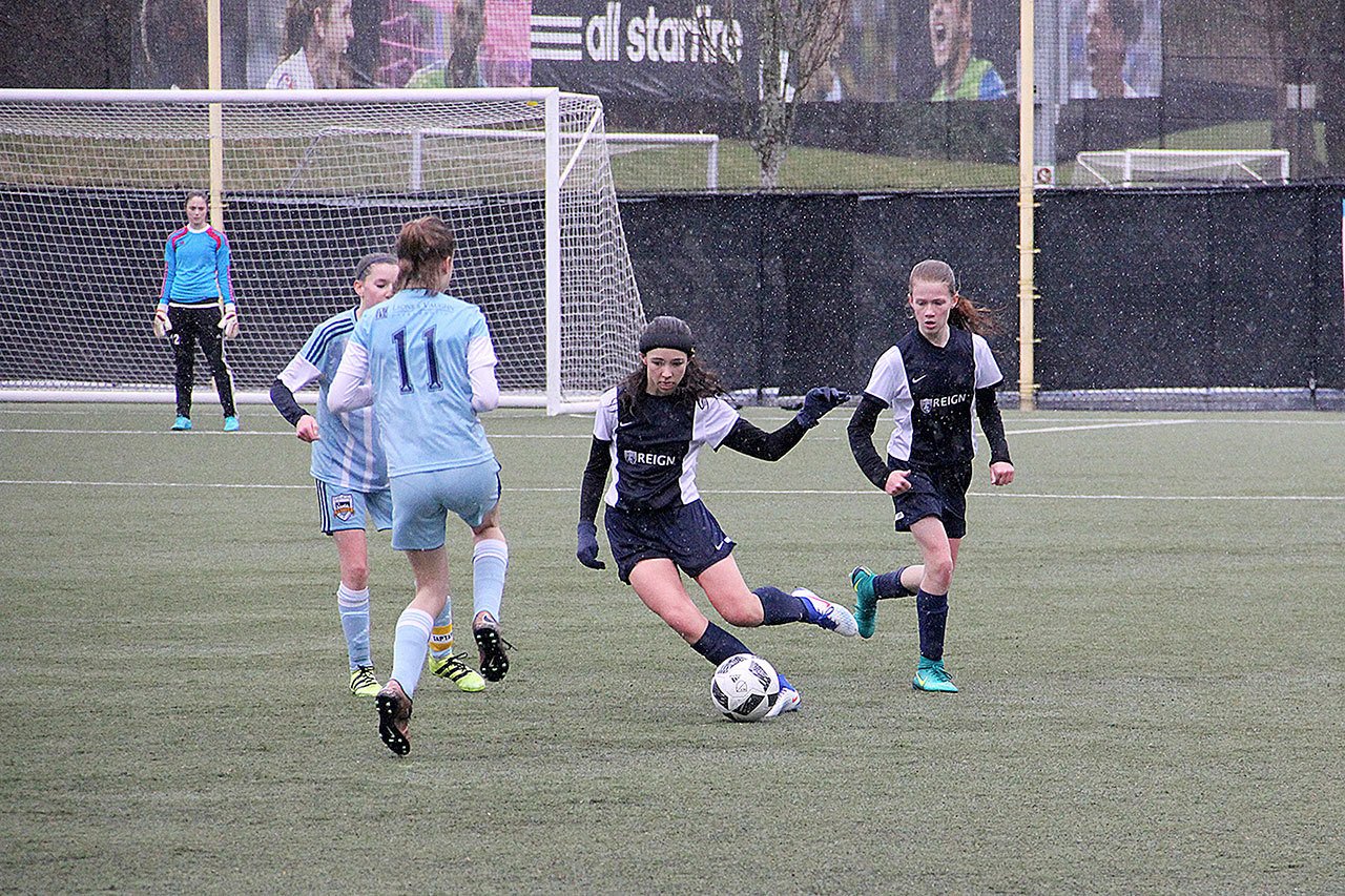 Contributed photo                                South Whidbey’s Kelly Murnane dribbles between two Bainbridge Island players with Liz Haines ready to assist. South Whidbey lost 2-1 in overtime in the championship match of the Washington State Youth Soccer Founders Cup on Feb. 5.