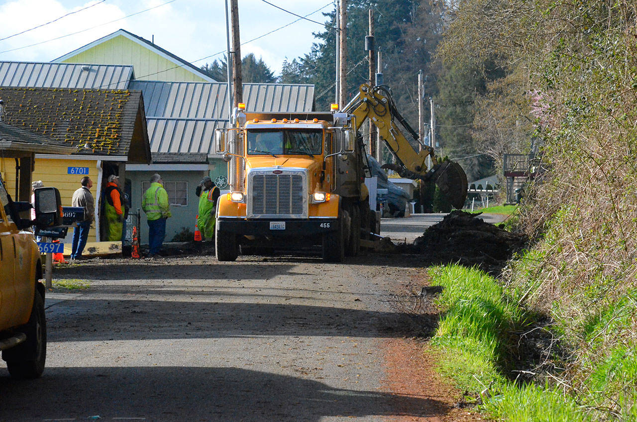 Justin Burnett/The Record &mdash; Island County Public Works road crews clear the last bit of debris from Columbia Beach Drive Monday morning. It was the second time they cleared the road that morning, following two slides that damaged a home.