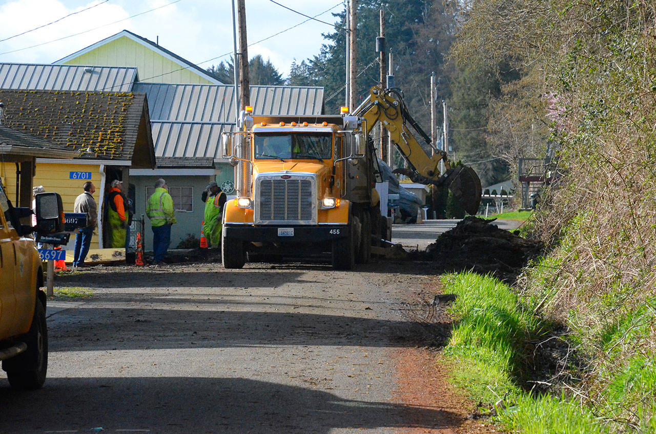 Justin Burnett/The Record — Island County Public Works road crews clear the last bit of debris from Columbia Beach Drive Monday morning. It was the second time they cleared the road that morning, following two slides that damaged a home.