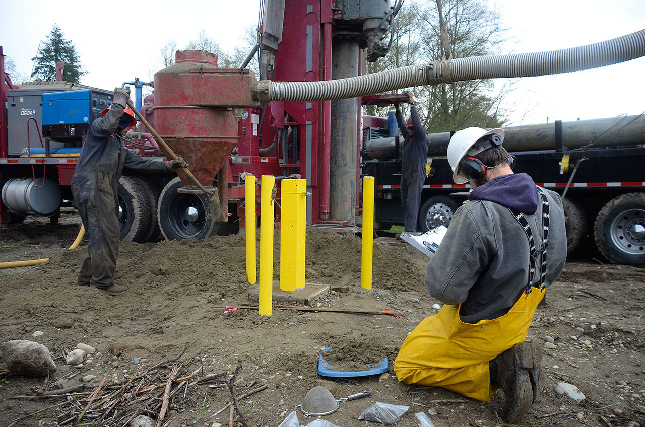 Justin Burnett/The Record — J. Glenn Mutti-Driscoll, a hydrogeologist with Seattle-based Pacific Groundwater Group, records soil samples at the Freeland Water and Sewer District’s 24-acre property between Highway 525 and Scenic Avenue. Two wells were drilled on the property this week to help determine drainage capacity of the site. Behind Mutti-Driscoll are Chris Haines (left) and Matt Call of Tacoma Pump and Drilling.