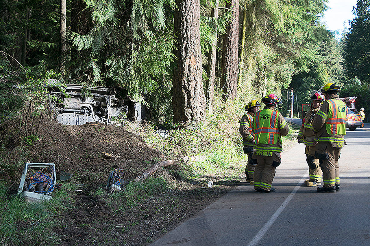 Kyle Jensen / The Record — Firefighters stand next to the scene of a wreck that left a vehicle on its side.